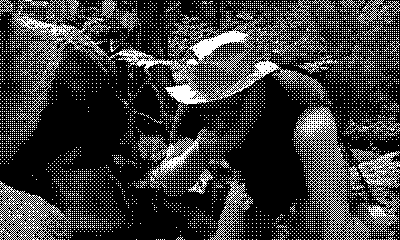 Dithered photograph of Adam Savage, wearing a duct tape hat, drinking from a river stream in a lush forest.